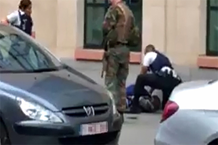 This screengrab shows police officials and a soldier looking at a man on the pavement in the city centre of Brussels on August 25, 2017, where a man is alleged to have attacked soldiers with a knife and was shot.