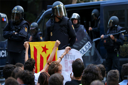 A protestor holds up an Estelada (Catalan independence flag) in front of a line of Spanish national police who surrounded the leftist Popular Unity Candidacy (CUP) party headquarters in Barcelona, Spain, September 20, 2017