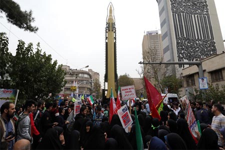 Iranians gather next to a replica of a Ghadr medium-range ballistic missile during a demonstration outside the former US embassy in the Iranian capital Tehran on November 4, 2017
