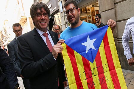 Carles Puigdemont poses next to a pro-independence supporter with a Catalan Estelada flag