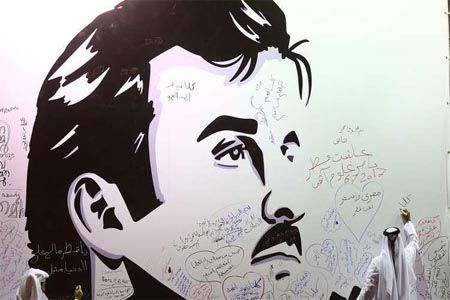 قطريون يكتبون تعليقات على جدار رسمت عليه صورة أمير قطر، الشيخ تميم بن حمد آل ثاني.