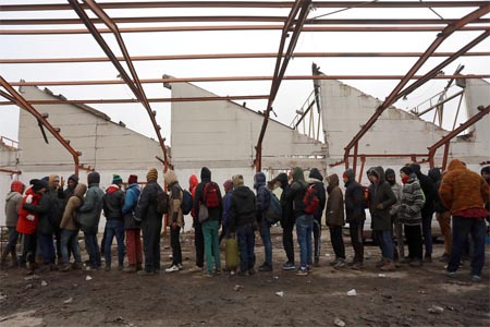 Migrants stand in line to receive free food inside an abandoned factory close to the Croatian border near the town of Sid, Serbia, December 19, 2017.