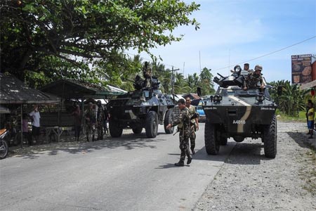 Philippine soldiers standing next to their armored personnel carriers as they man a checkpoint along a highway near the clash site between government troops and militants.