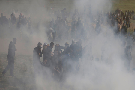 Palestinians run from tear gas fired by Israeli troops during clashes, during a tent city protest along the Israel border with Gaza, demanding the right to return to their homeland, east of Gaza City March 30