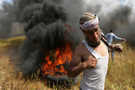 Palestinian runs during clashes with Israeli troops, during a tent city protest along the Israel border.