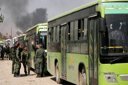 Syrian troops stand next to buses carrying militants and their families before they are evacuated, at Harasta highway outside Jobar, in Damascus, Syria March 25, 2018.