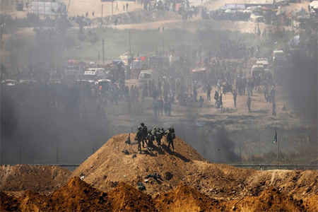 Israeli soldiers are seen next to the border fence on the Israeli side of the Israel-Gaza border.