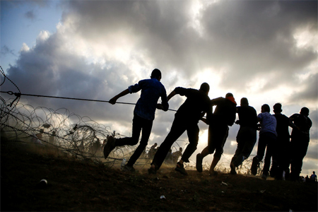 Palestinan protesters pull onto a cable tied to a barbed-wire fence as they try to pull down a section of the fence with Israel, east of Jabalia in the central Gaza Strip on June 1, 2018.