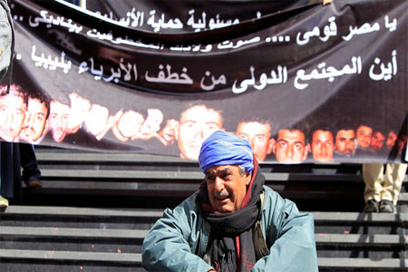 A family member of one of Egyptian Coptic Christian workers who have been kidnapped in the Libyan city of Sirte, sits crying in front of a banner with pictures of the workers, in Cairo, Feb. 13, 2015. (Reuters)