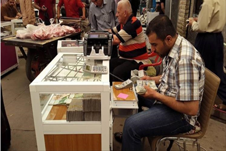 عراقي يعُدّ حزمة دولارات في سوق تداول العملات ببغداد