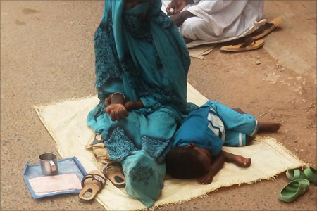 مرياما النيجرية مع الطفل الذي يرافقها في التسول (الجزيرة نت)