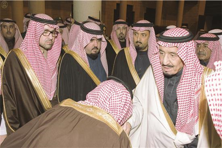 سعودي يقبل يد الملك سلمان وخلفه ولي العهد مقرن خلال تلقيهما البيعة في الرياض امس