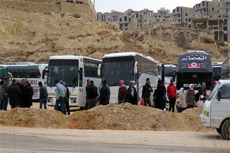Syrians gather around buses as they prepare to leave the town of Ain al-Fijah, in the Wadi Barada region, on January 14, 2017