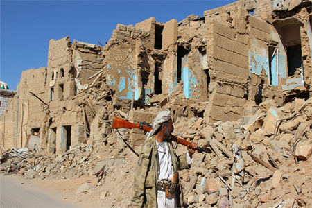 A Houthi armed man walks past destroyed houses in the old quarter of the northwestern city of Saada, Yemen January 11, 2017