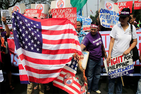 Protesters burn a U.S. flag and a mock flag with pictures of U.S. President-elect Donald Trump outside the U.S. embassy in metro Manila, Philippines January 20, 2017.
