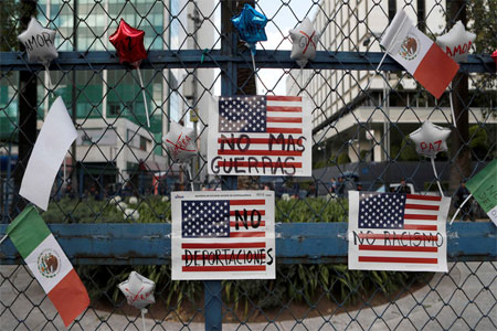 Signs that read in Spanish "No more wars," "No more deportations" and "No racism" hang from a fence in front of the US Embassy, during a march called by a local women's movement against US President Donald Trump in Mexico City, Friday, Jan. 20, 2017. (AP)
